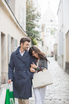 Couple carrying shopping bags on cobblestone street near Sacre Coeur Basilica, Paris, France