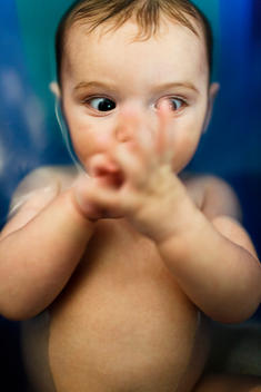 An infant girl discovers her hands during her bath.