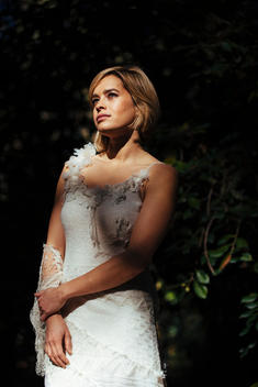 portrait of woman looking up in her wedding dress in the woods.