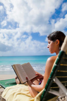 Woman reading book on beach, St Maarten, Netherlands