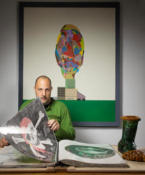 Art dealer, Stefan Simchowitz sits at a table in his home looking at a book of artwork