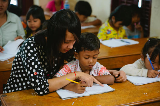 A teacher helps a child with his schoolwork at Empowering Youth in Cambodia\'s Impact School in Phnom Penh, Cambodia.