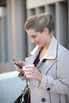 Young businesswoman texting on smartphone in city