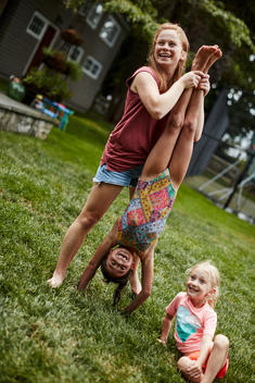 Woman playing with girl hanging upside down