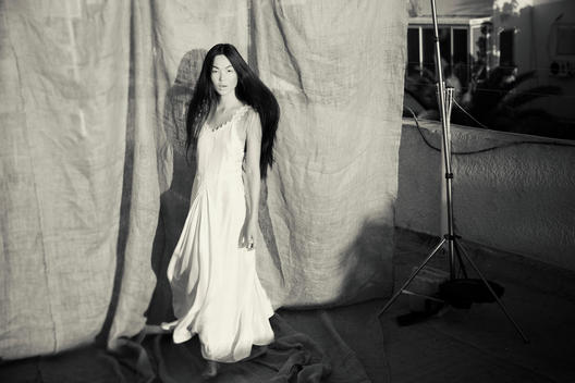 Asian model with a white dress and dramatic face looking into the camera