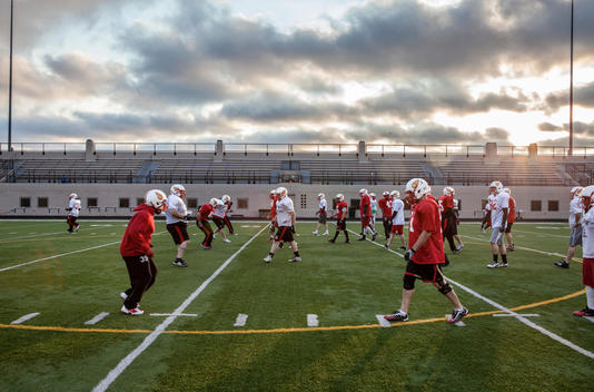 A football team runs drills during a practice. The team is an intramural team of men ranging in age from late teams to 40s.