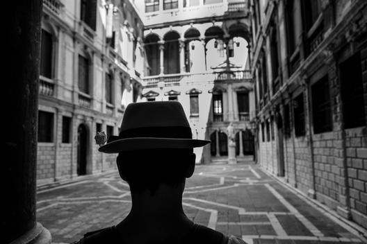 A beautiful hat and rose, the back of a woman\'s head takes you into the scene of an old villa in Venice, Italy.