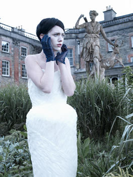 Fashion Story Model In A White Dress In Front Of An Old Statue Crying