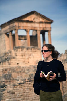 A female tourist checks her guidebook in front of Roman Capitol at Dougga (Thugga), a UNESCO World Heritage Site, the best-preserved Roman town in North Africa.