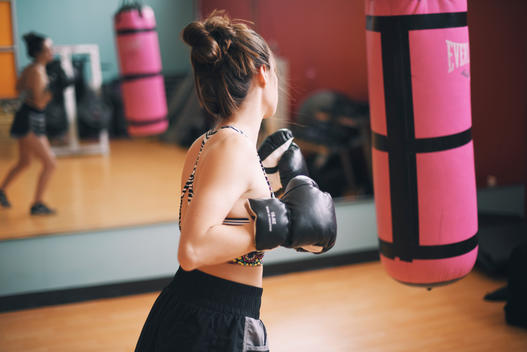 Girl at the gym boxing a pink punching bag