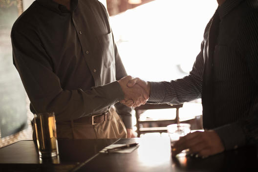 Two businessmen shaking hands in wine bar