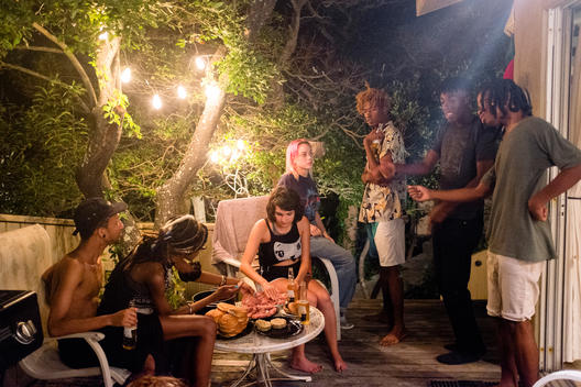 exterior lifestyle group shot of a group of young men and women socializing in the backyard, at night