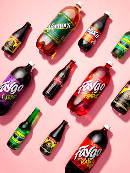 Assortment of soda pop bottles on pink