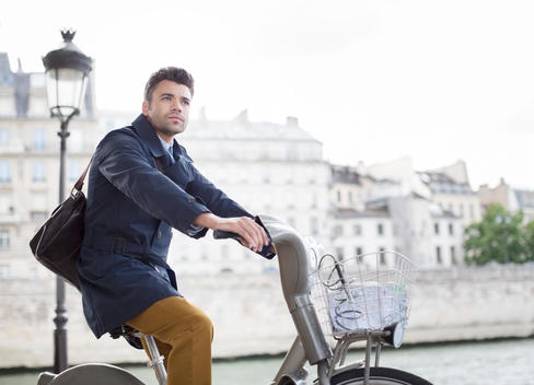 Businessman riding bicycle along Seine River, Paris, France