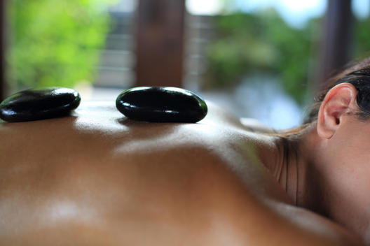 Woman receiving hot-stone massage therapy
