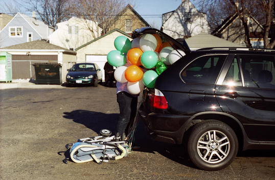 Man Putting Balloons Into Back Of Car Outside Party Store