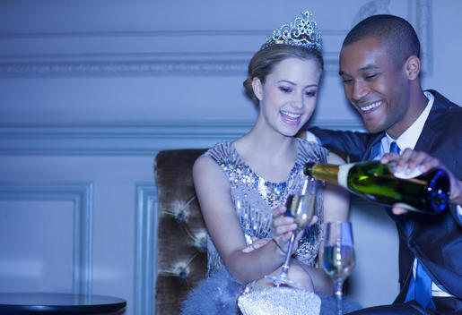 Man pouring champagne for woman in tiara