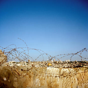 A View Of The Old City And Disputed Center Of Jerusalem With The Holy Sites Of The Western Wall And The Ibrahimi Mosque Seen Through Barbed Wire On The Outskirts Of The City.