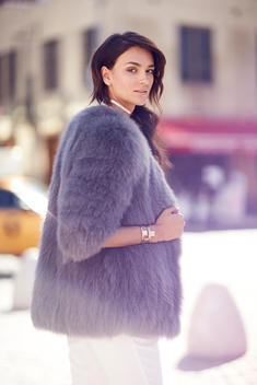 A photo of a woman in a purple fur coat with her hair swept over one shoulder
