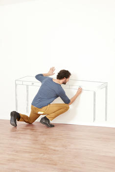 Man creating outline of table on wall