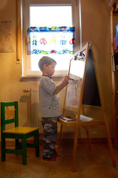 Focused Young Boy Painting Alone At His Easel