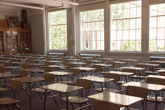 A classroom of desks with a bank of windows