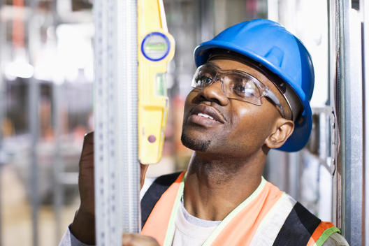 African American worker checking metal on site