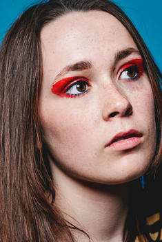 Teenager with a brace, looking into distance, with red eye make up and brunette hair