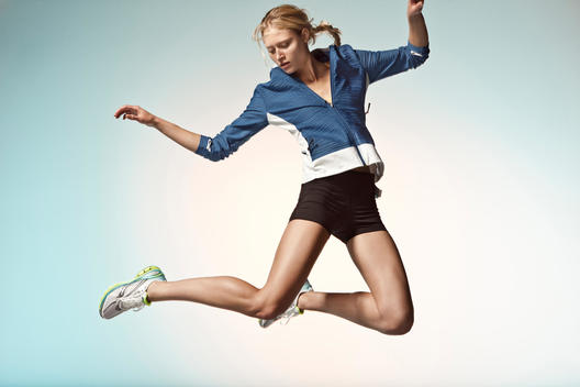 Blonde athletic girl jumping in studio