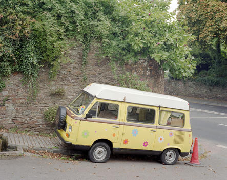 A yellow campervan painted with flowers in the two of Totnes. Totnes is an ancient market town on the mouth of the river Dart in Devon. The town is attempting to become a blueprint for communities to make the change from a life dependent on oil to one tha