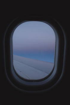 view through passenger airplane window at dusk with wing