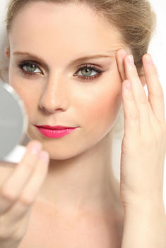 girl applying makeup in mirror