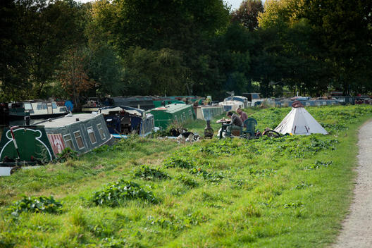 House Boat Residents Relax On The Bank Of The Canal.