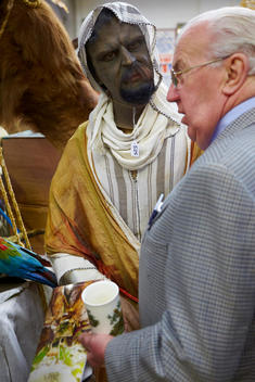 Model Of Black Man In Middle Eastern Clothing Looking At Old Man At Auction