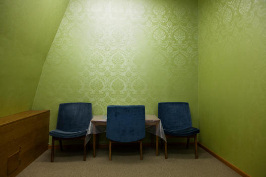 The living room of the most famous Tito\'s bunker: a very small room, carpeted with green wallpaper and furnished with three blue chairs and a small table. This 6500 square meter bunker was one of the most expensive structures in the former Yugoslavia. Bui