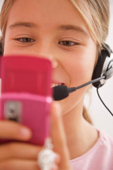 Close up of a smiling girl wearing a headset and holding a mobile phone