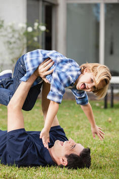 Playful father lifting up son in garden
