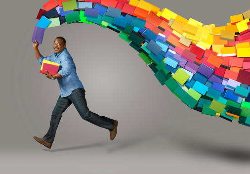 Actor LeVar Burton leaps in the air with a trail of books creating a rainbow above him