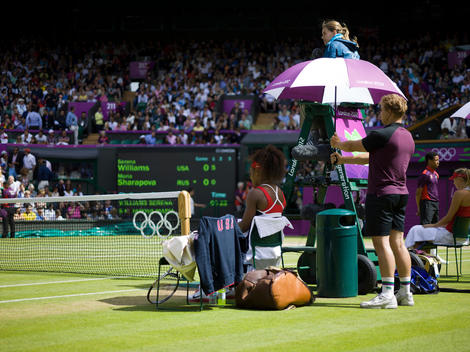 Serena Williams (USA) and Maria Sharapova (Russia) take a rest during their Women?s Final match on Centre Court at the London Olympics. They are shaded from the sun under umbrellas held by a ball boy. The match was held at Wimbledon, the home of the All E