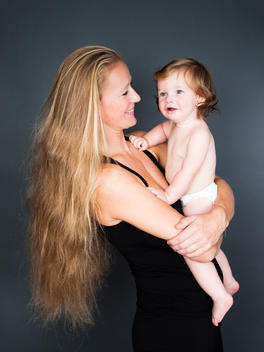 Nine month old baby boy being cuddled by his blonde haired athletic mother.