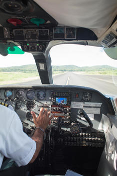 view of runway from inside aircraft\'s cockpit with pilots\' hand on the throttle