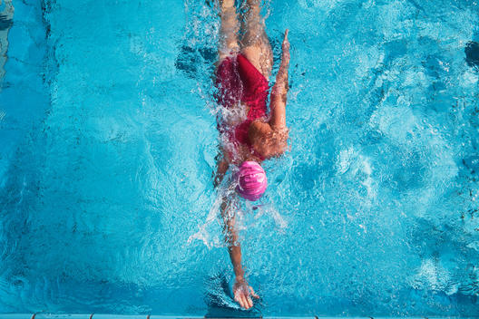 Woman swimming in pool, rear view