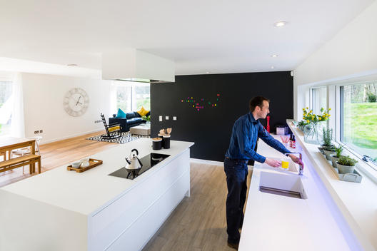 Minimal kitchen interior with male at the Woods residential property designed by Scott Brownrigg, Bedfordshire, UK.