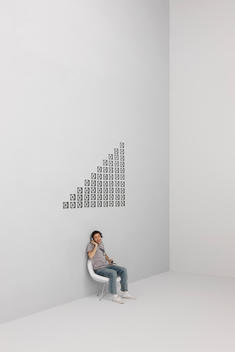 Man singing along with music playing on MP3 player, CD cases arranged in pattern on wall