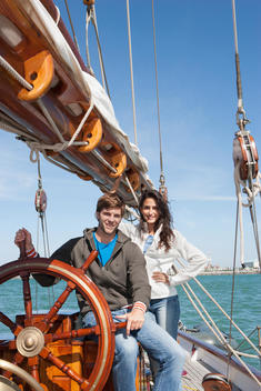 Caucasian couple at helm of sailboat