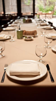 Table Setting With Glasses, Forks, Knives, White Plates, Bread And Oil