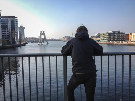 Germany, Berlin, Elsen bridge, young man looking at Spree with molecule man