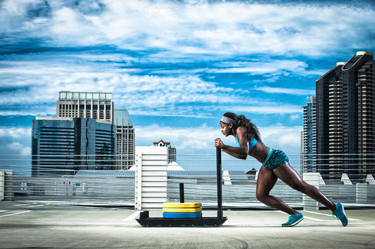 An athletic girl pushing a weight sled.