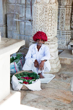 old Indian man wearing turban and selling flowers at the entrance of Ranakpur main Hindu temple