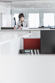 Businesswoman standing in office on smartphone